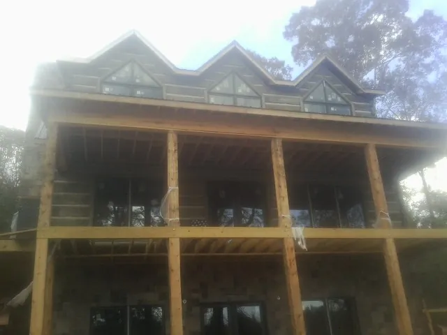 Dormers and porch framing on a large log home under construction — Roof Coating work by our crew in Onalaska