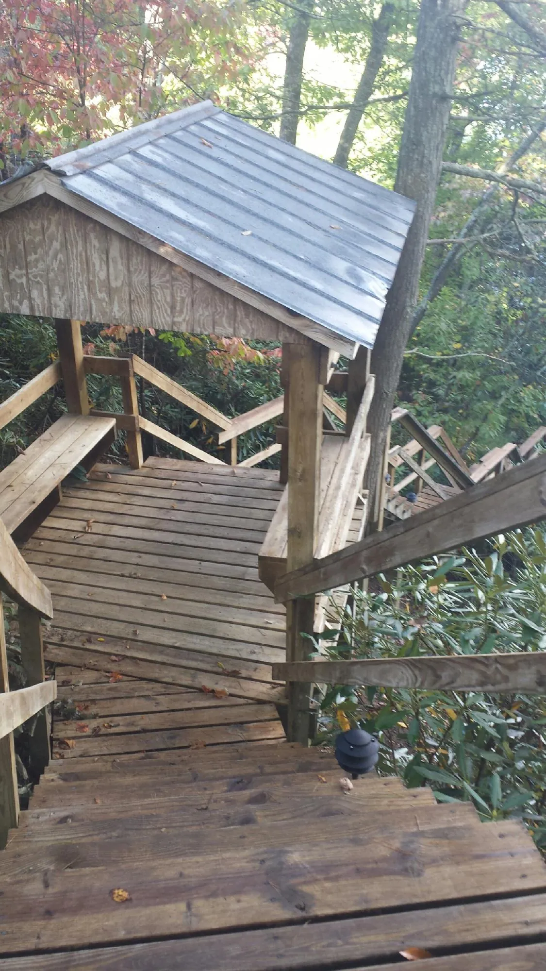 Metal roofed shelter over wooden steps on a wooded walkway — Skylight Repair & Installation work by our crew in Onalaska