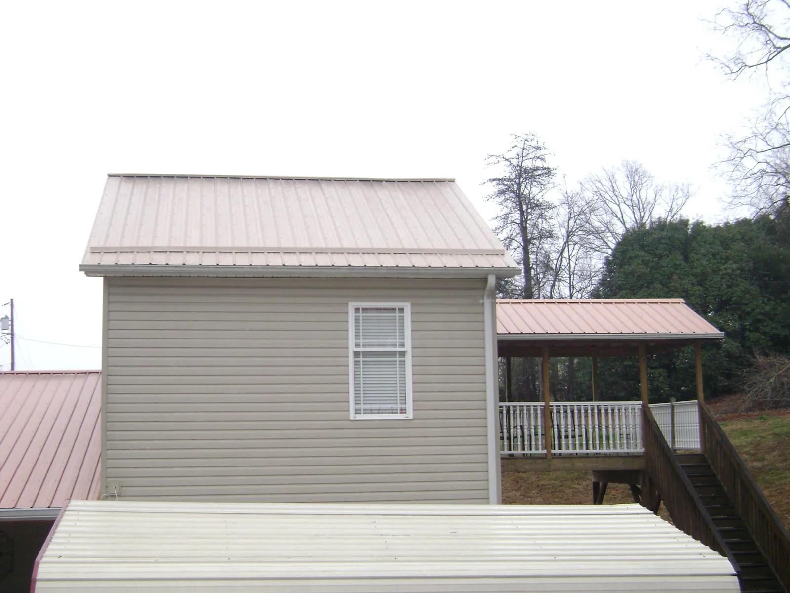 Tan metal roofs on a two story addition and attached porch, from a Roof Replacement job in Onalaska