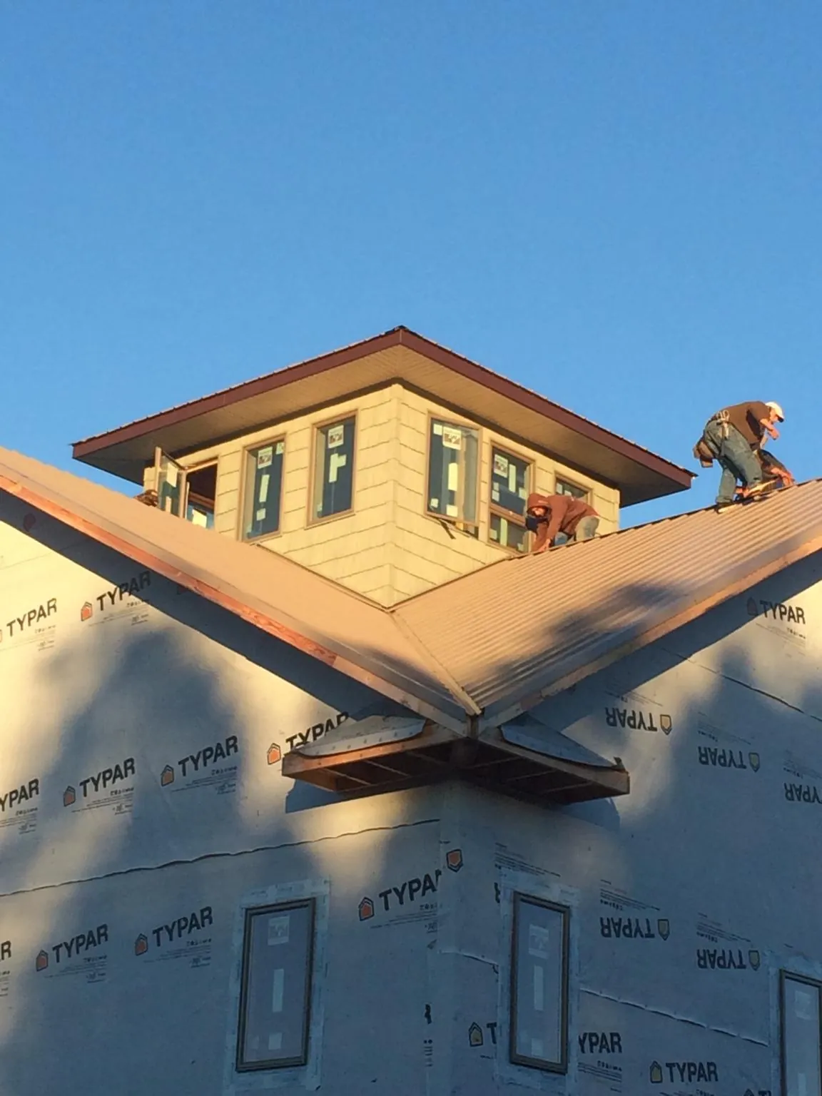 Roofers working around a rooftop cupola on a new metal roof at sunset — Roof Waterproofing in Onalaska by Roofing Brothers